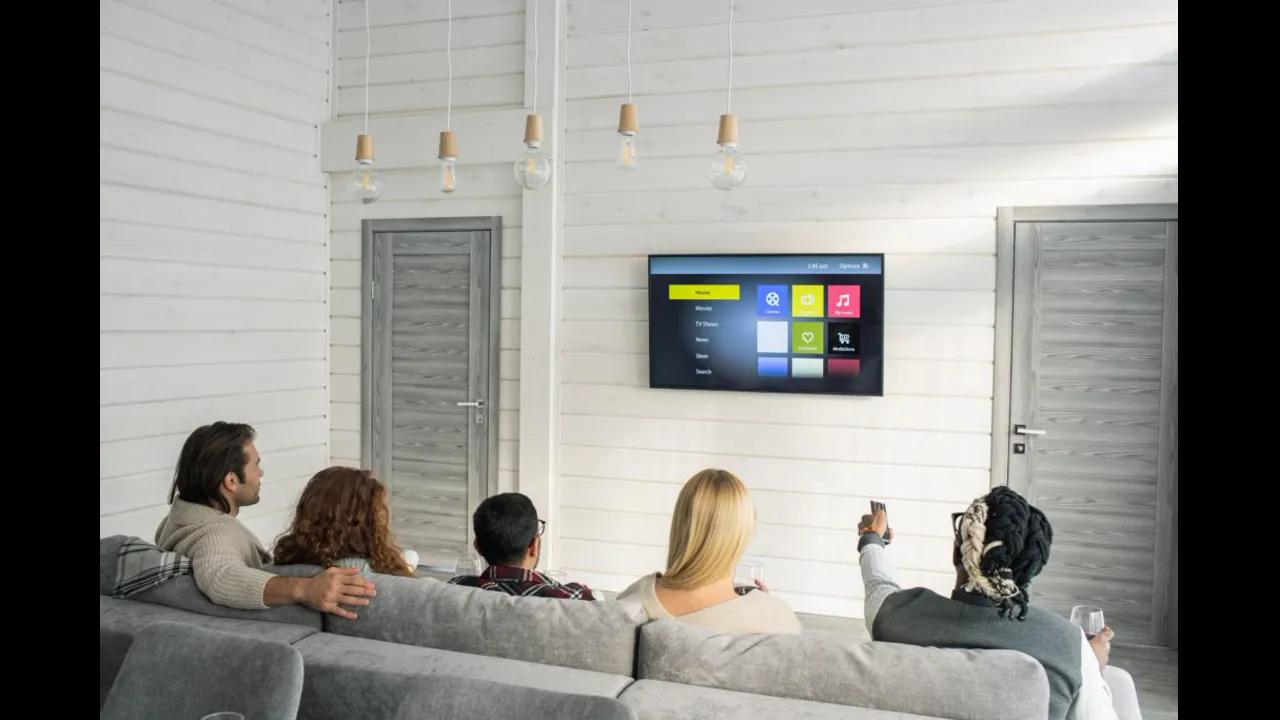 Friends on a sofa watching a television showing a streaming menu