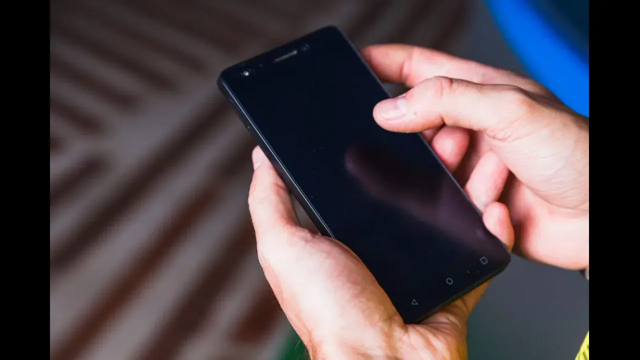 Hands holding an older Android phone with on-screen navigation buttons
